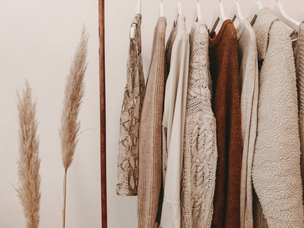 Fall clothing in closet. Long sleeve shirts and sweaters on hangers.