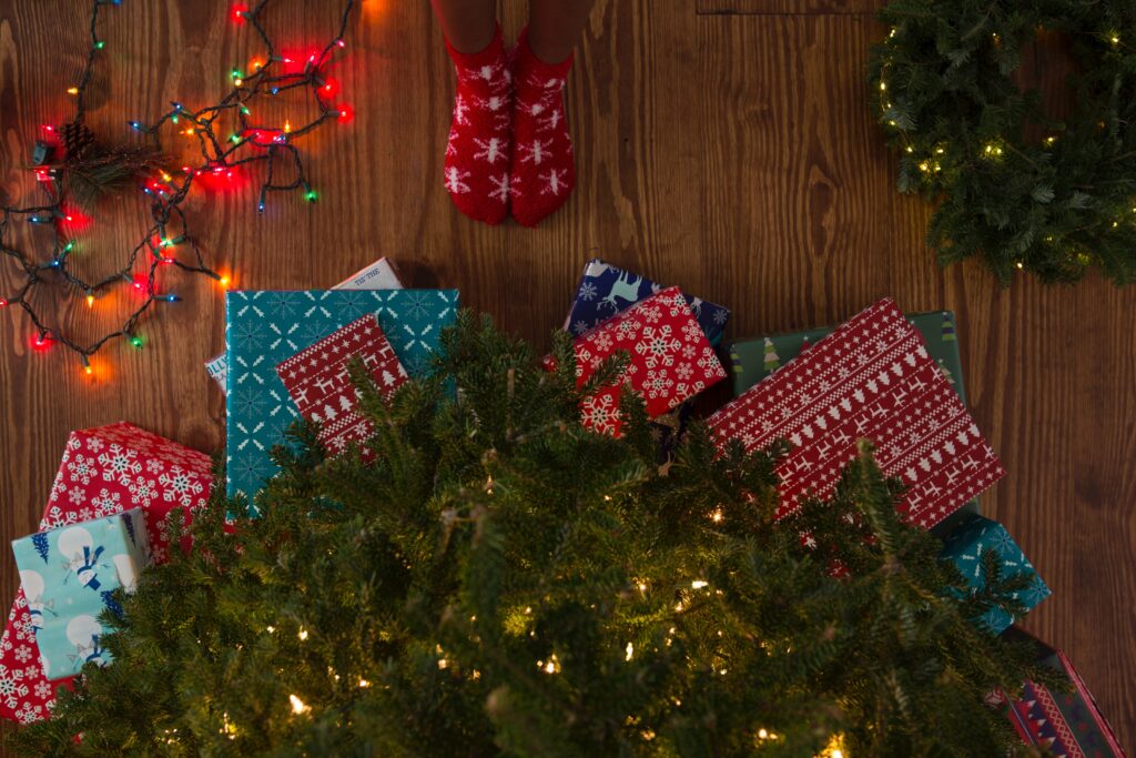 Christmas gifts for kids. Kids standing at Christmas tree opening presents.